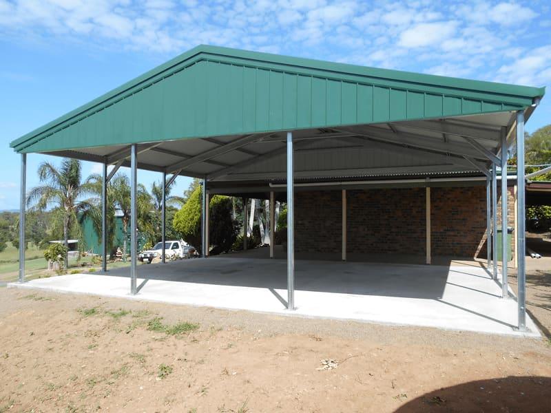 Green gable carport on a new concrete slab with palm trees