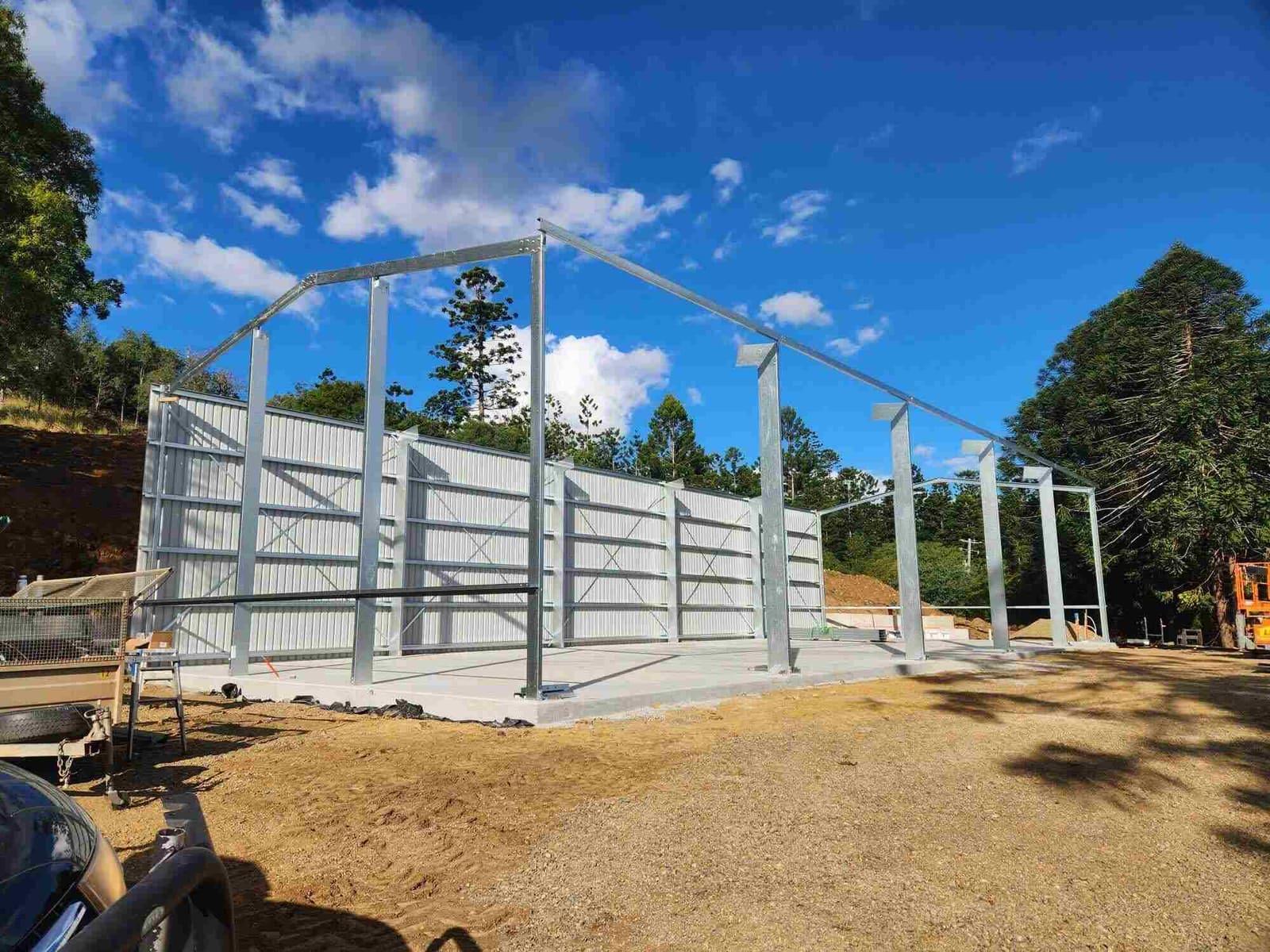 Galvanised steel portal frames and girts going up on a building site, partly clad