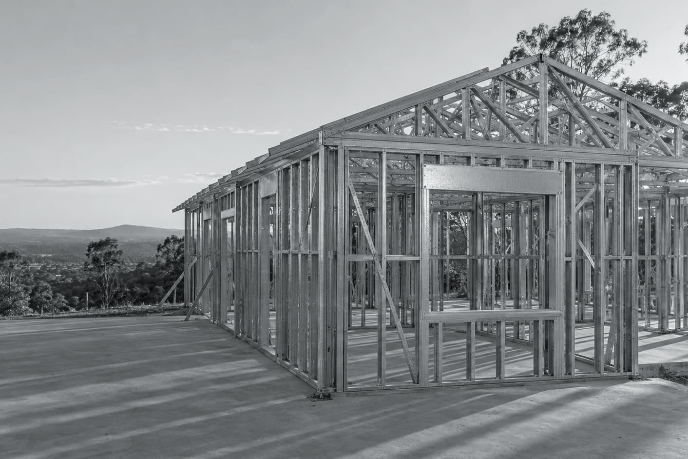 Illustrative image: a house framed in light gauge steel walls and roof trusses on a concrete slab