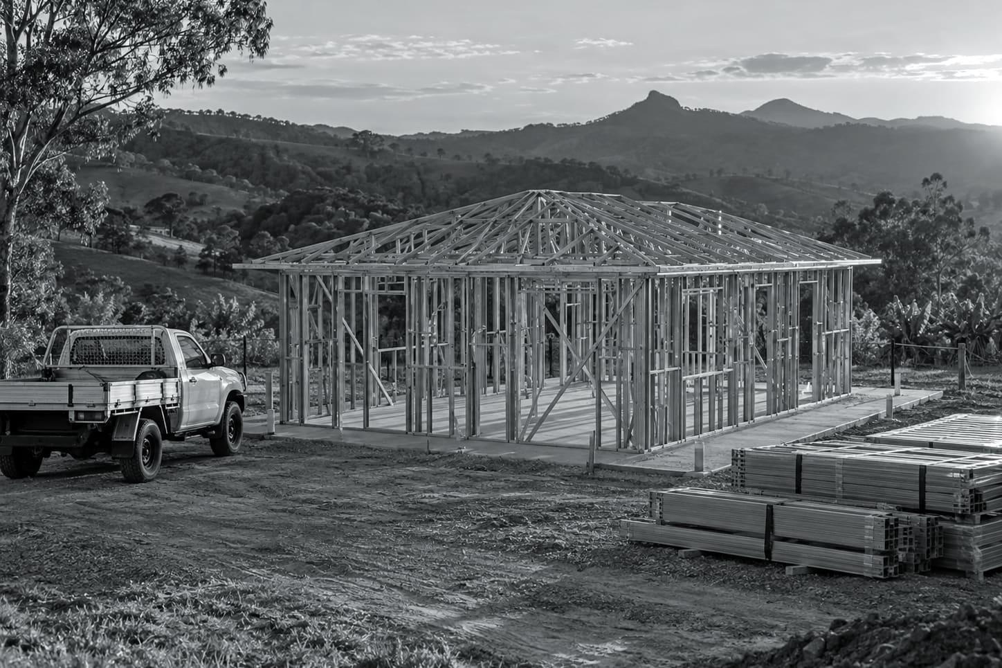 Illustrative image: steel wall frames and trusses standing on a slab at a rural Queensland building site
