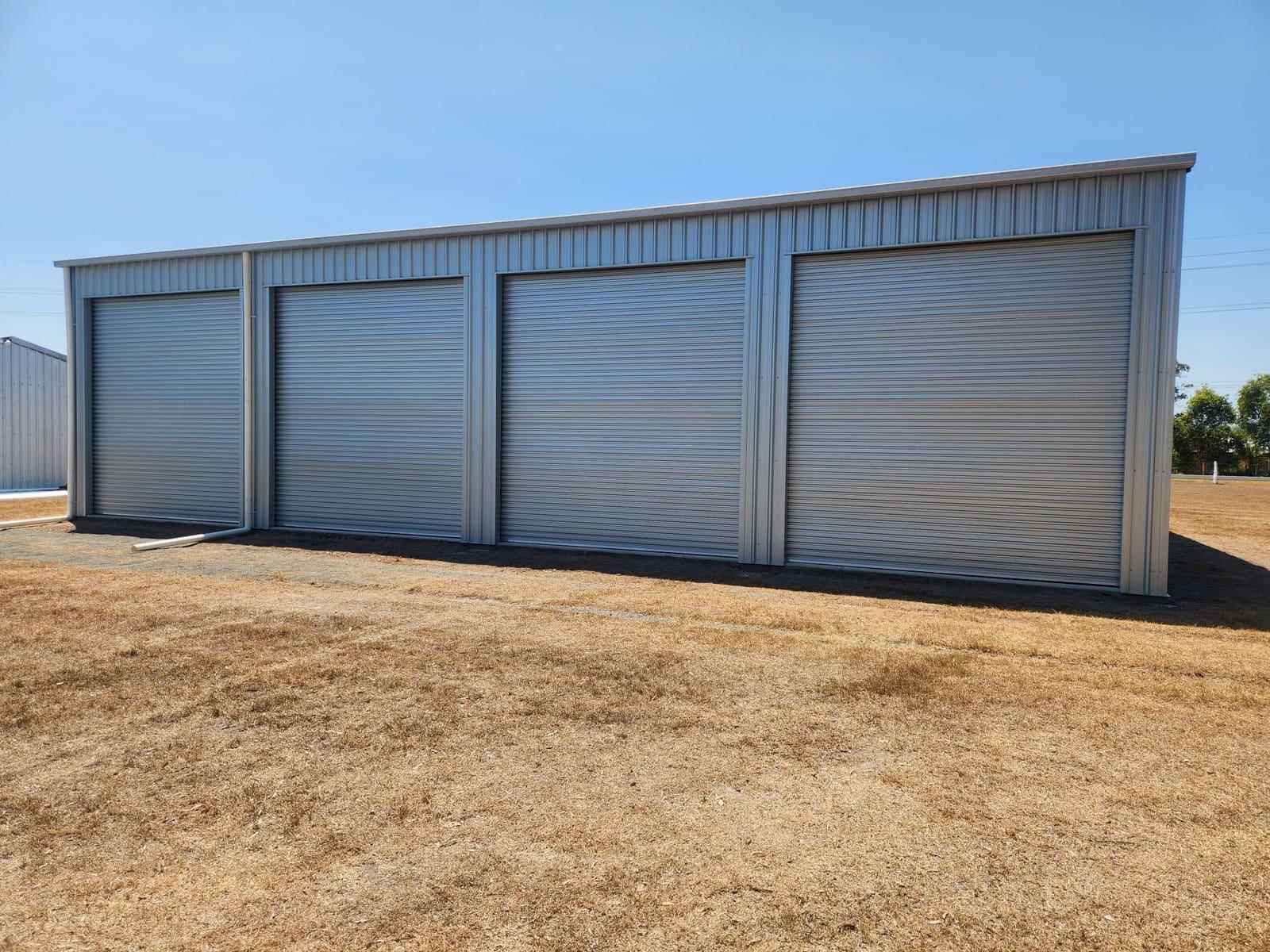 Zincalume steel shed with four roller doors on a dry site
