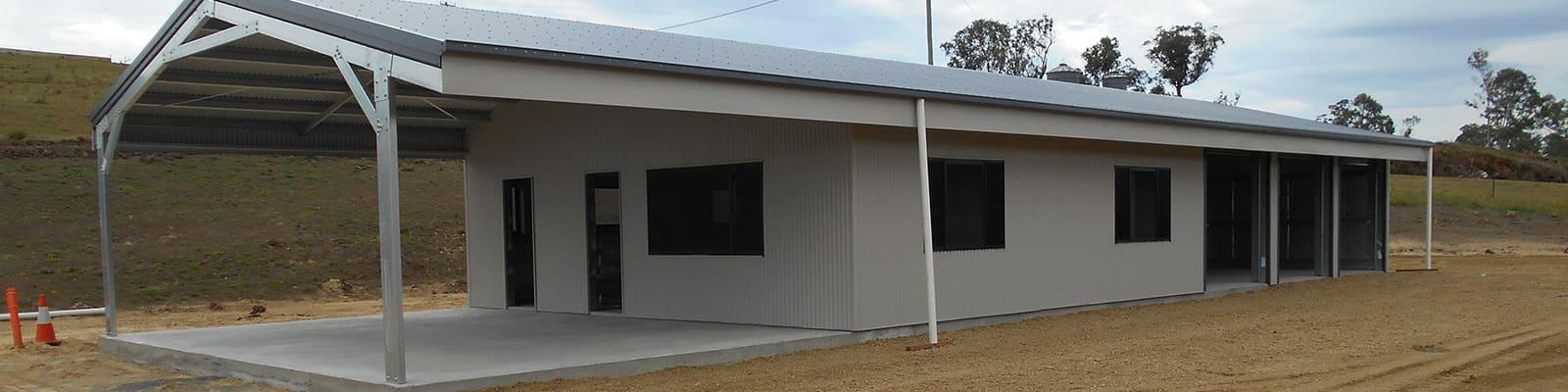 Long cream garaport with an awning on a rural property