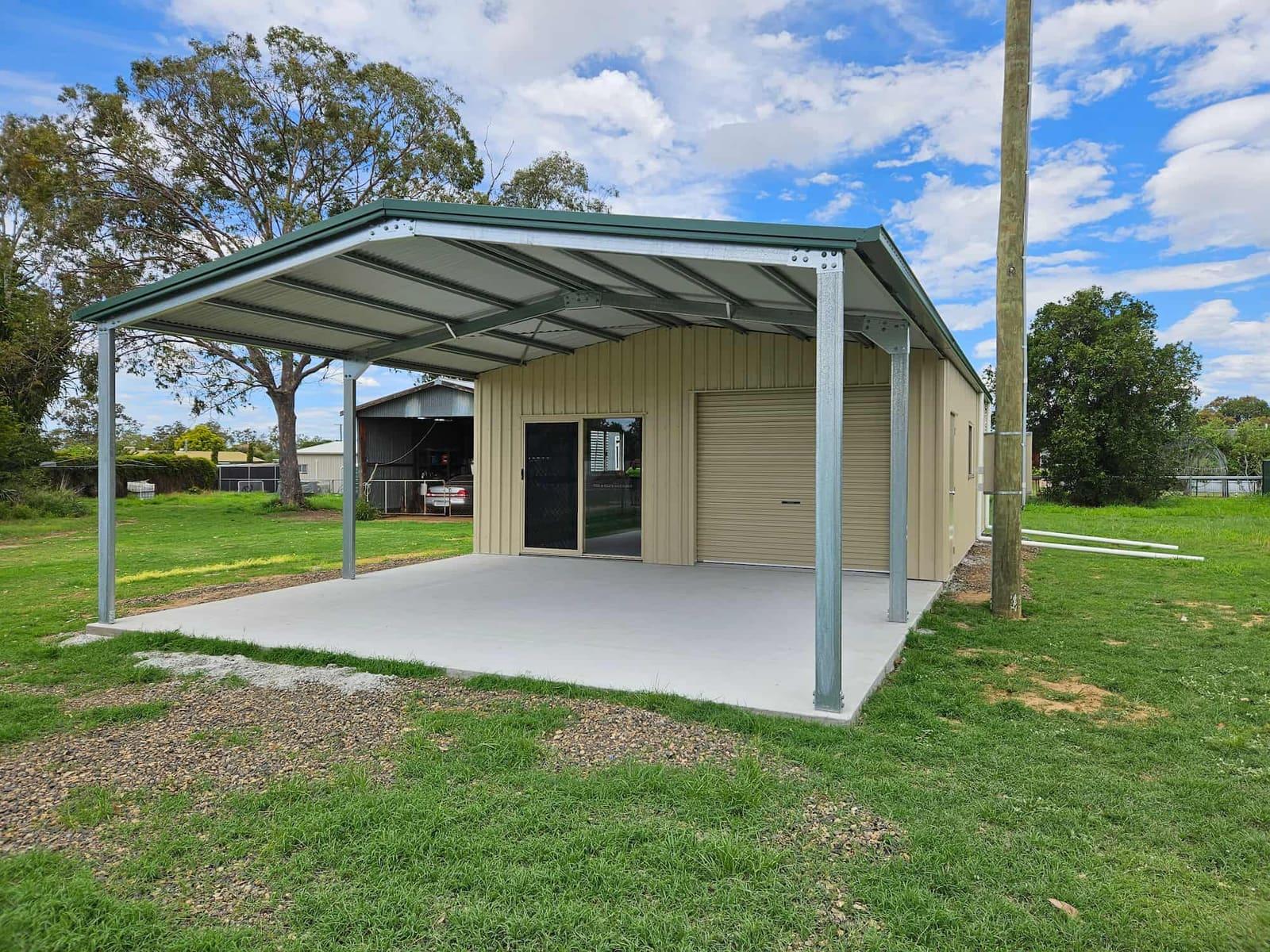 Cream gable shed with a green carport awning on a slab among gum trees