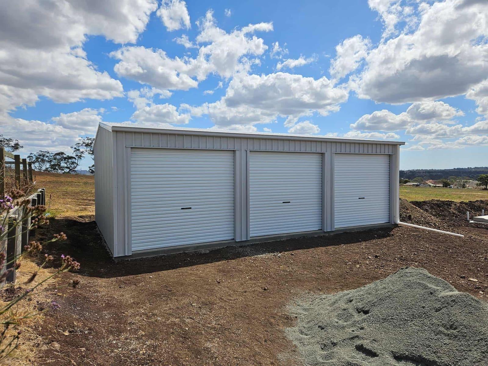 White three-door steel garage on a rural lot